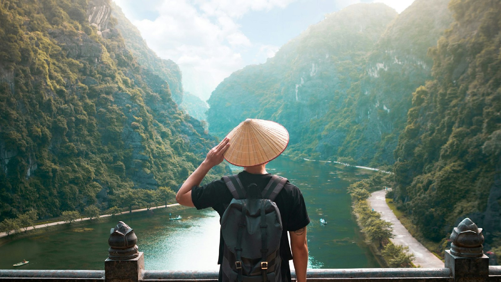 Voyageur en chapeau conique contemplant la baie de Ha Long depuis un belvédère