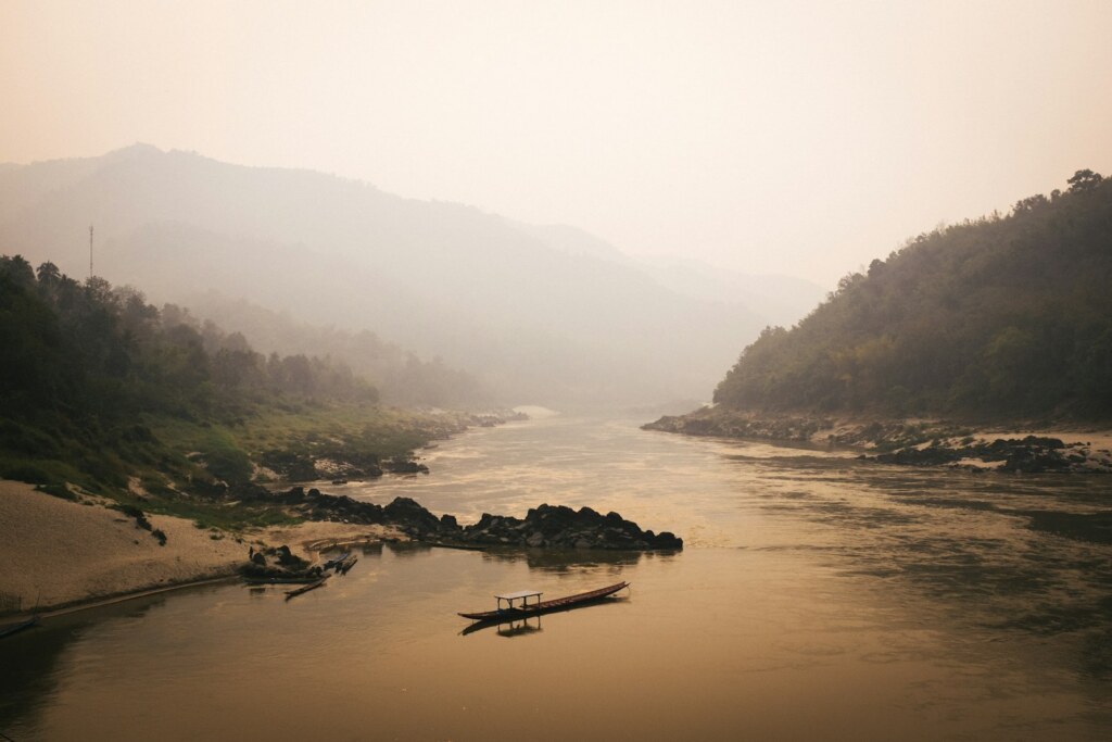 Le Mékong dans la brume du matin avec une pirogue, nord du Laos